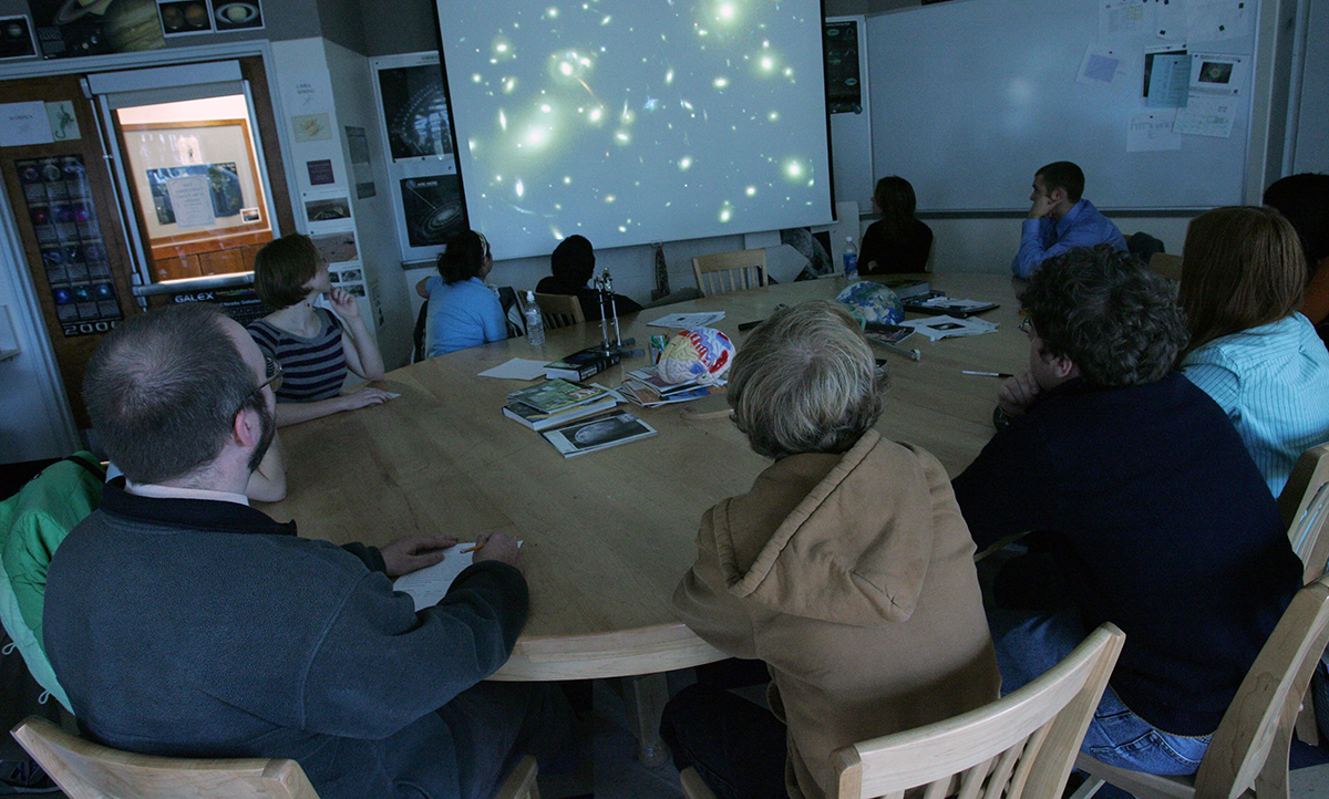 An astronomy class around the Harkness table with Instructor John Blackwell in the Phelps Science Center.