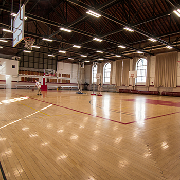 A student practices basketball inside of Thompson Gym