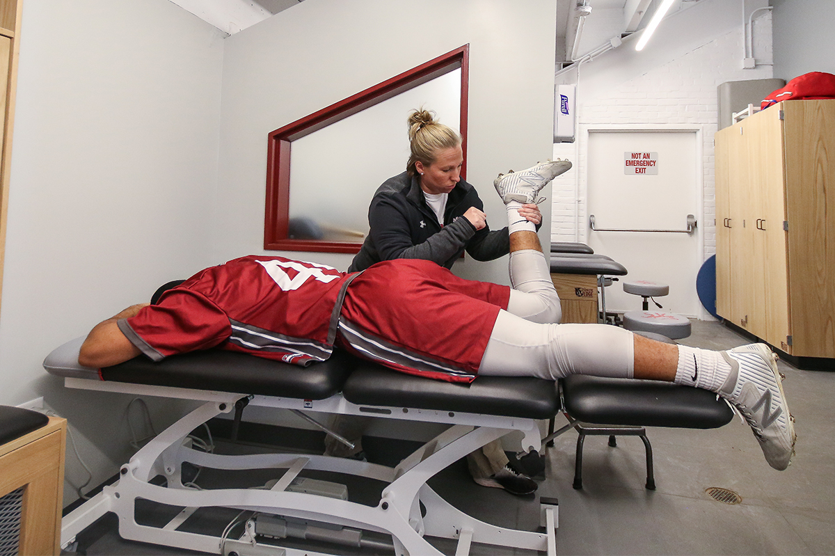 An athletic trainer stretching an athlete in the Bravo Room