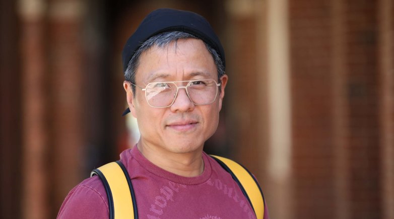 Man with glasses, t-shirt and yellow backpack straps.