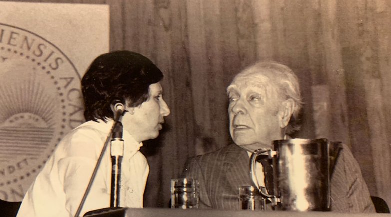 An old photo of two people sitting at a table talking