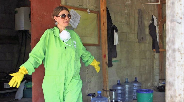 Sasha Kramer in a protective suit, plastic gloves and sunglasses