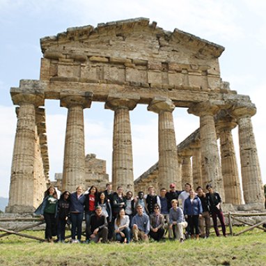 A group of students posed in front of classical ruins