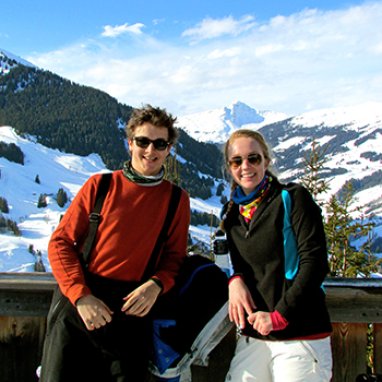two smiling people in front of snow covered mountains