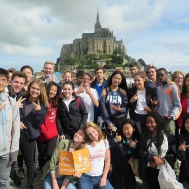 A group of students smiling with Mont Saint-Michel in the background