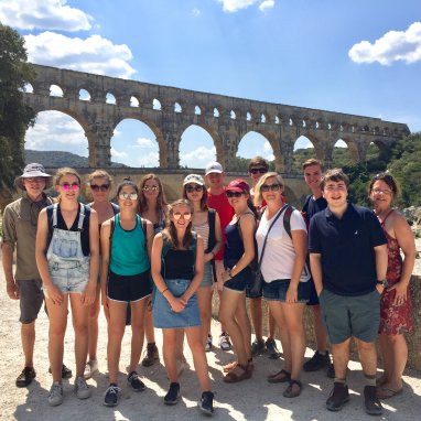 Students gathered for a photo in front of a Roman bridge in Italy